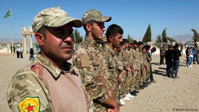 A group of YPG fighters listen to a speech in Derik