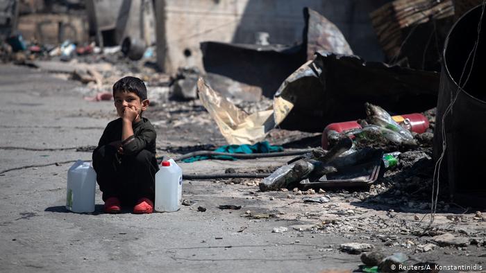 A child sits between two water containers in the Moria refugee camp (photo: Reuters/A. Konstantinidis)