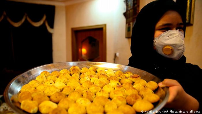 An Iraqi woman carrying a tray of cookies