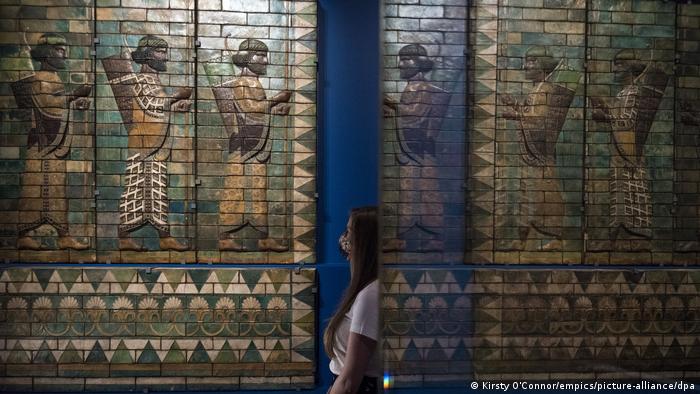 A museum staff member wearing a mask looks at the tiled work "The King's Bodyguard"