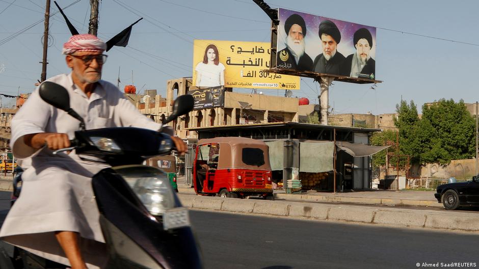 A man drives his motorbike near a poster of the late Grand Ayatollah Mohammed Sadiq al-Sadr, his son Iraqi Shia cleric Muqtada al-Sadr, and Iraq's late Shia cleric Mohammed Baqir al-Sadr, in the Sadr City district of Baghdad, Iraq, 21 June 2021 (photo: Ahmed Saad/Reuters)