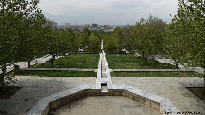 Blick in die Parkanlage Bagh-e-Babur in Kabul. Im Vordergrund ein Brunen, der kein Wasser hat. Im Hintergrund sind Rasenflächen zu erkennen.