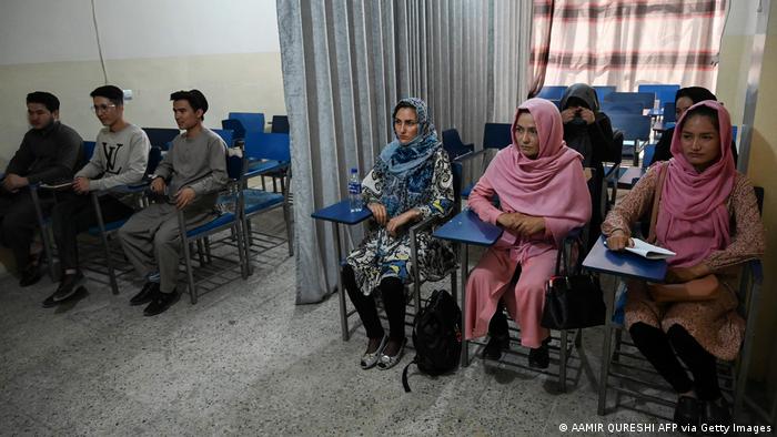 Männer und Frauen sitzen getrennt in einem Klassenzimmer.