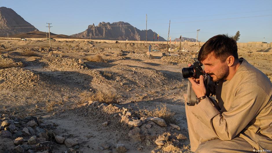 Szene aus dem Film "Ghosts of Afghanistan": Ein Mann fotografiert in einer Wüstenlandschaft, die als Friedhof dient.