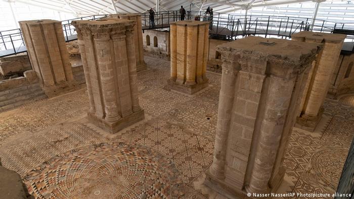 People on walkways above the mosaic tiled floor and in between tall columns