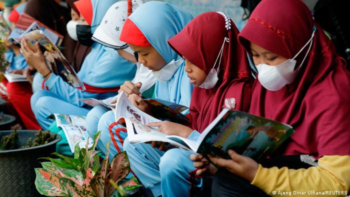 Die Kinder sitzen gemeinsam und lesen