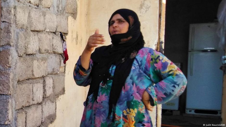 Woman in a headscarf stands outside her home in Mosul (photo: Judit Neurink/DW)