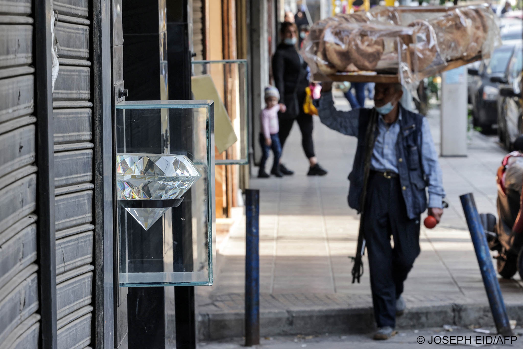  A street vendor walks past shuttered jewellery shops in Beirut's Burj Hammoud neighbourhood on 14 December 2021 (photo: Jospeh Eid/AFP) 