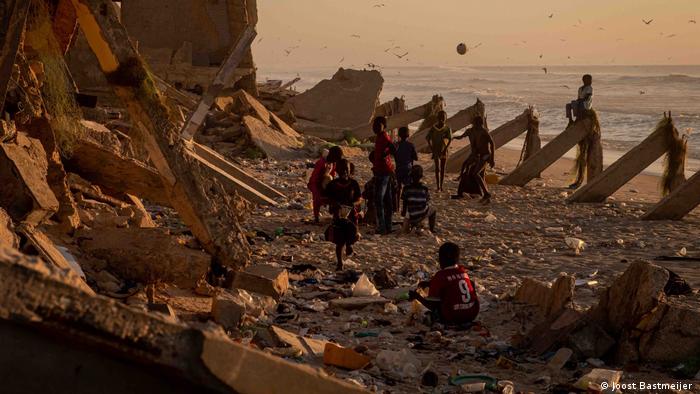 Children playing on a beach with debris at sunset in Guet Ndar, Senegal