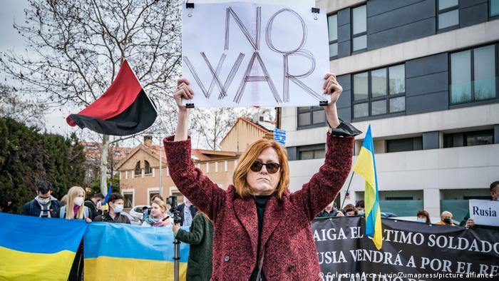 A protester in Madrid holds up a sign reading "No War"