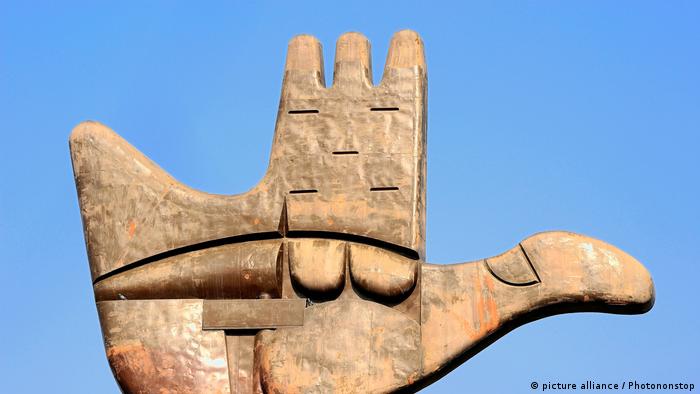 A stone sculpture showing the palm of a hand merging with the image of a dove