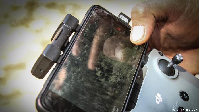 Someone holds a kind of mobile phone screen with a metal holder on which there is a kind of joystick