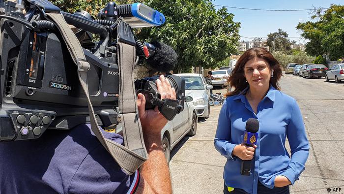 Journalistin Schirin Abu Akle auf einer Straße mit Mikrofon vor einer Kamera