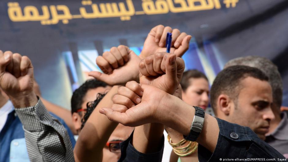 Journalists protest against curbs to freedom of speech in front of a placard in Arabic which reads "Journalism is not a crime!" (photo: صحفيون يحتجون على القيود المفروضة على حرية التعبير أمام لافتة باللغة العربية مكتوب عليها "الصحافة ليست جريمة". 