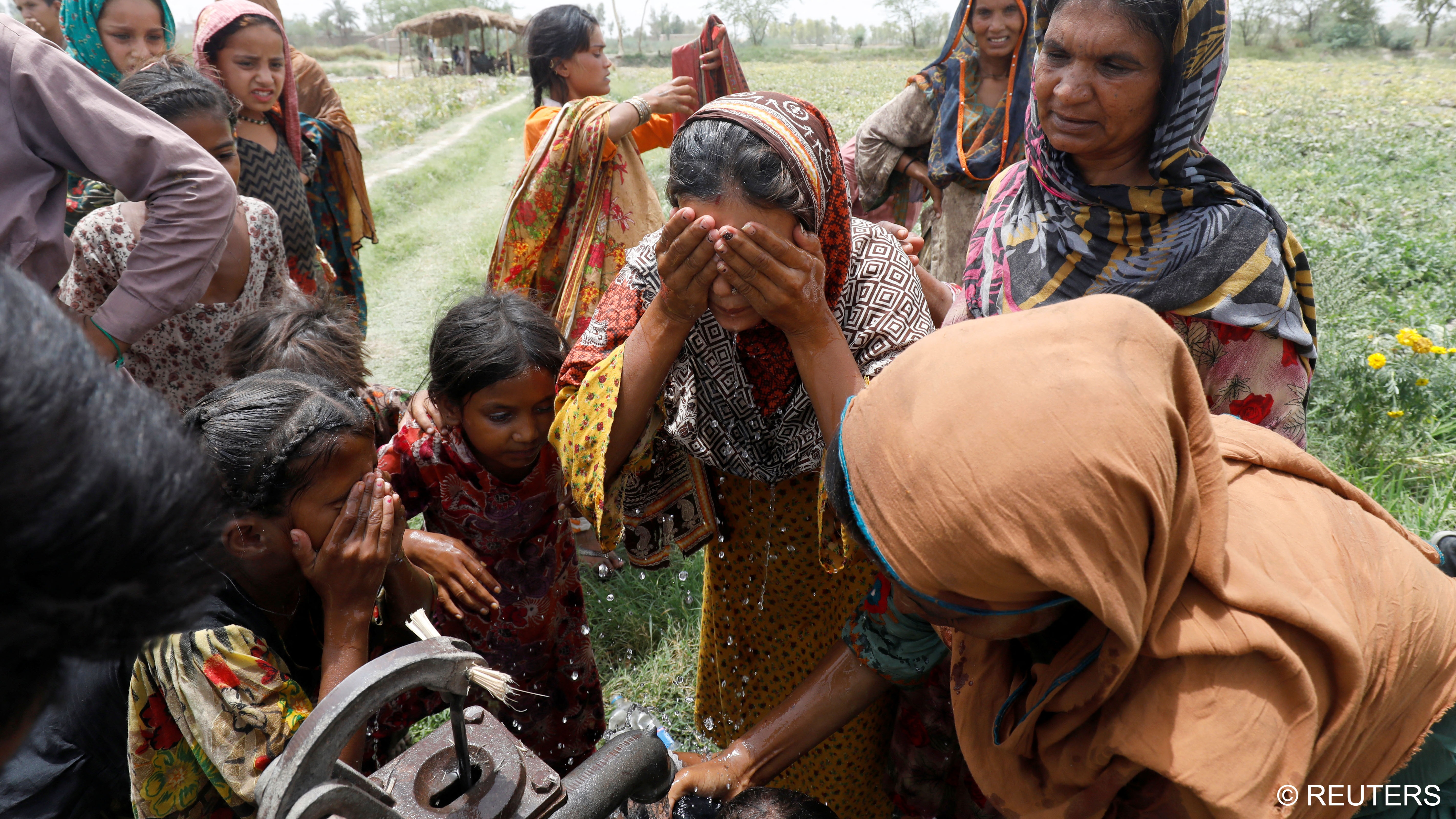 Women and children wash themselves after work at a muskmelon farm (photo: Reuters/Akhtar Soomro)