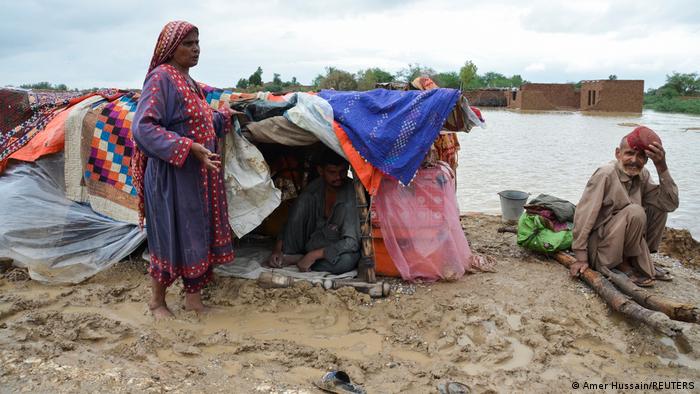 A family in Balochistan stands next to their makeshift hut