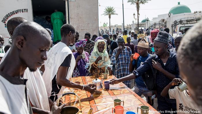 Volunteers hand out coffee to pilgrims on the street near the mosque