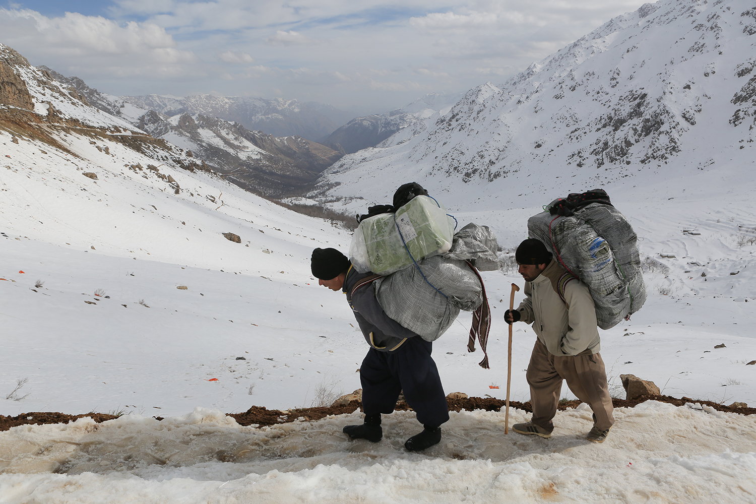 Two men with large packs walk along a track against a snowscape (photo: Konstantin Novakovic)