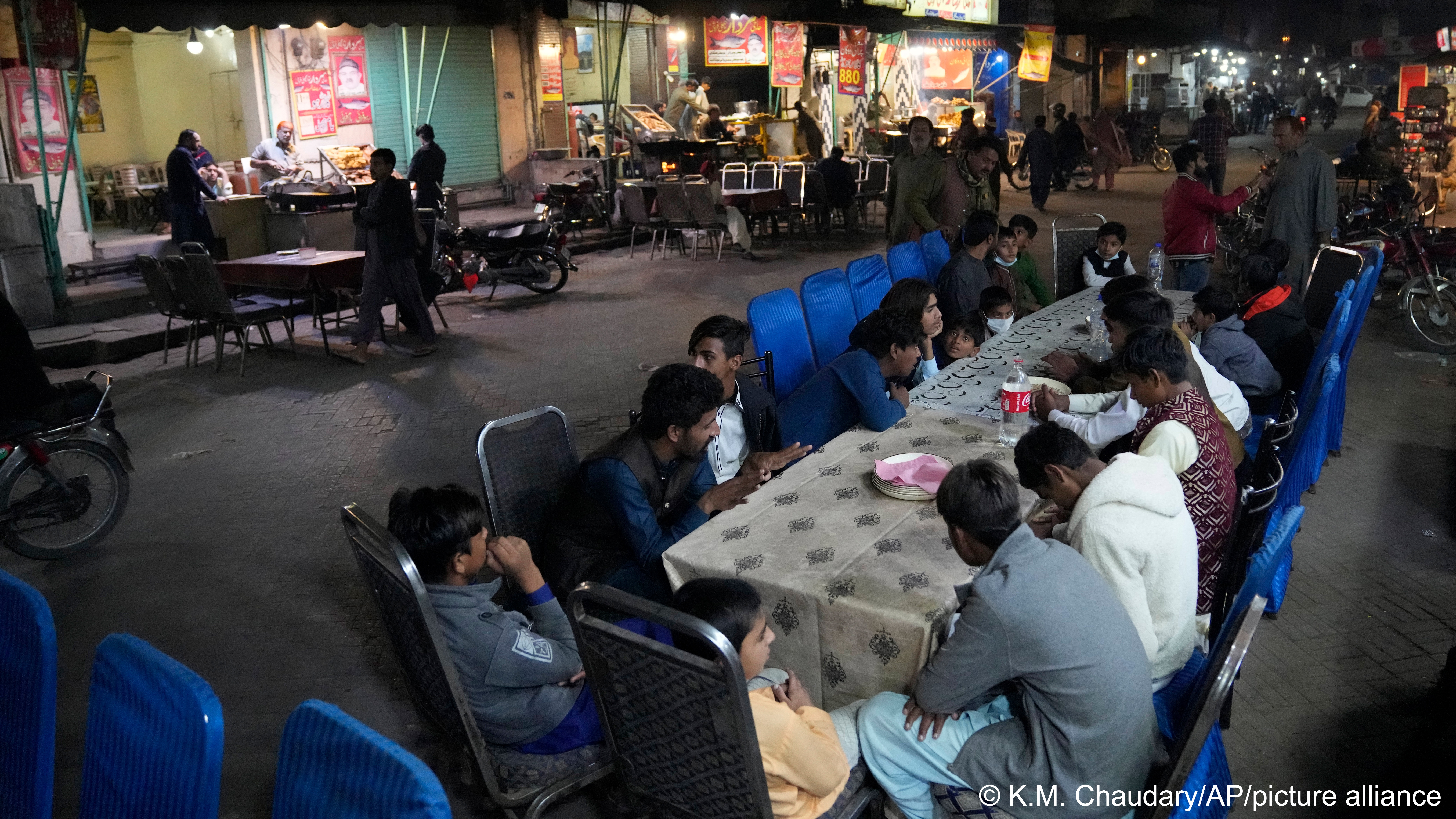 People wait to be served dinnert in the famous food street of Gawalmandi, an old area of Lahore, Pakistan, 11 December 2022 (photo: AP Photo/K. M. Chaudary)