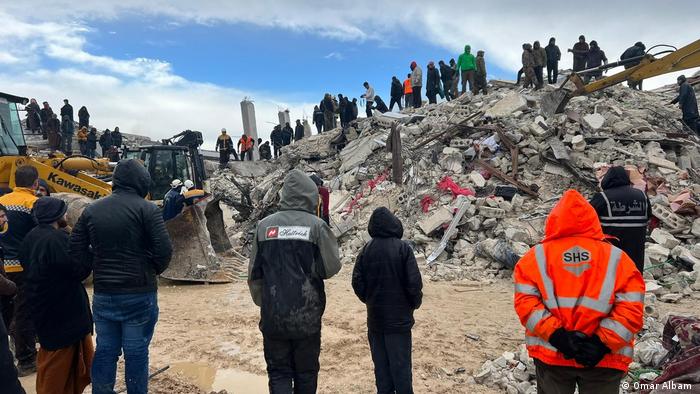 People on a pile of concrete rubble. It is impossible to guess what once stood there