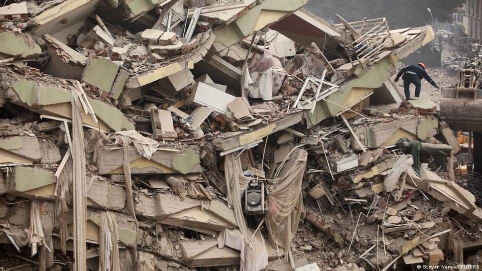 A person scrambles up a collapsed building in Kahranmanmaras, Turkey (image: Stoyan Nenov/REUTERS)