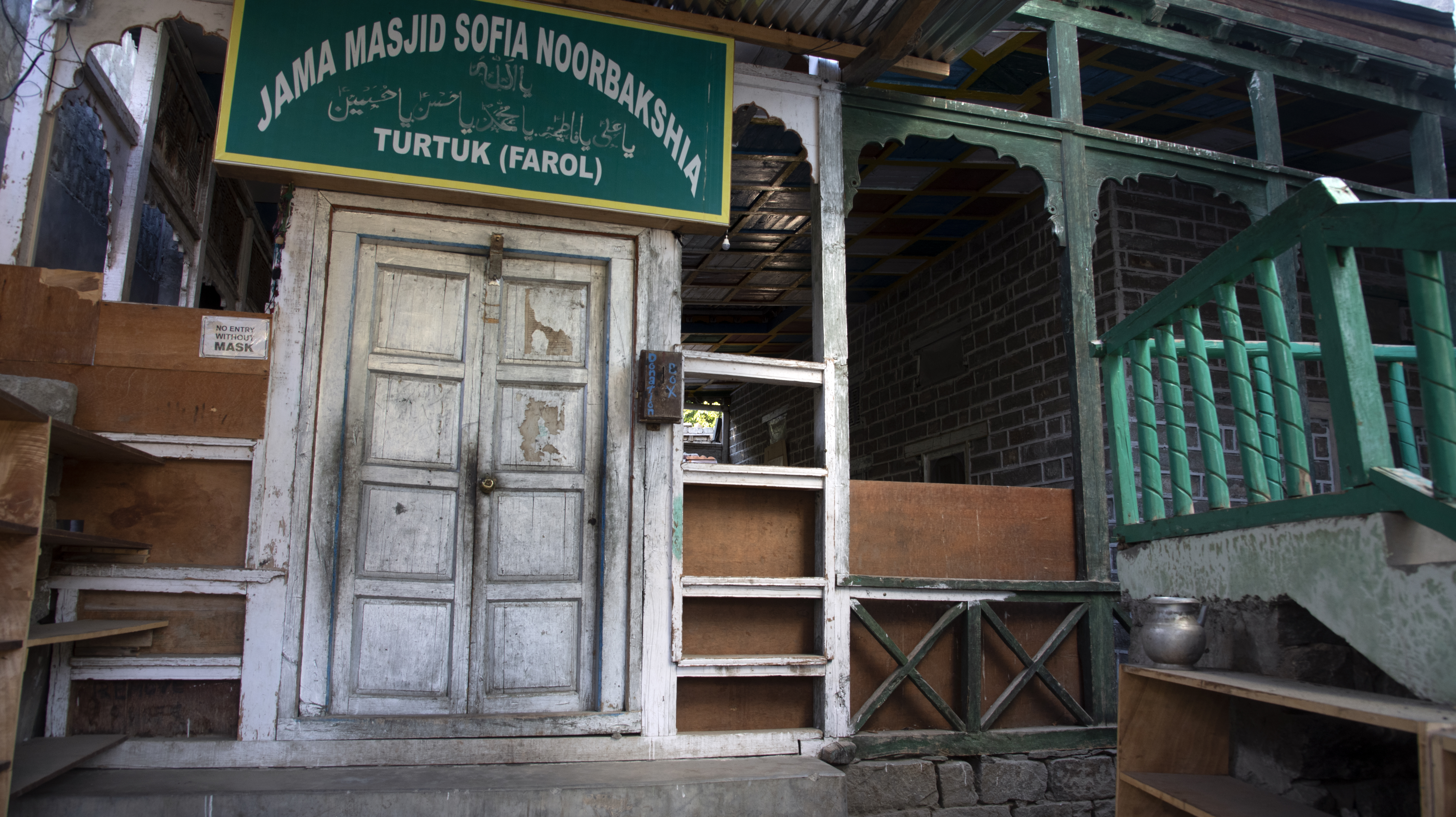 A sign indicating the Muslim nature of the village community hangs on the facade of a wooden building (image: Sugato Mukherjee)