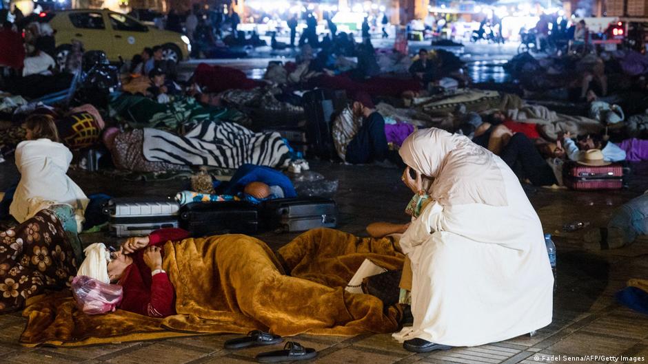 Woman in white on the street, surrounded by numerous people lying on the ground