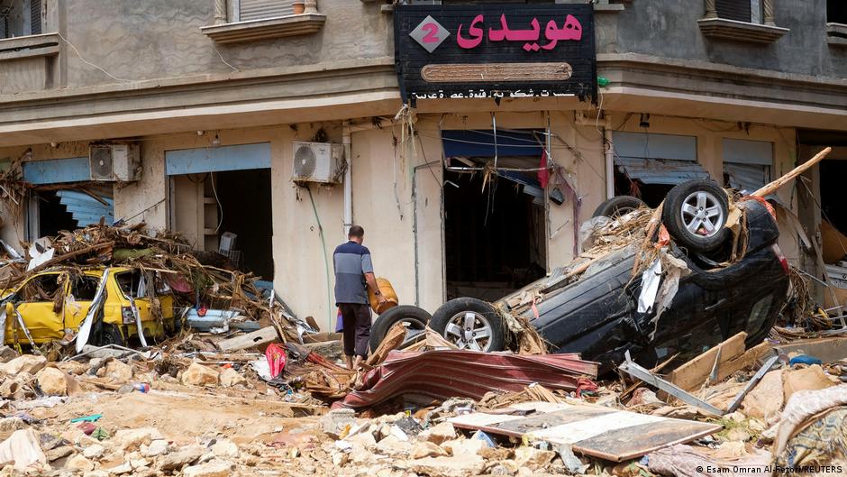 A man walks through the rubble with a gas cylinder in his hand