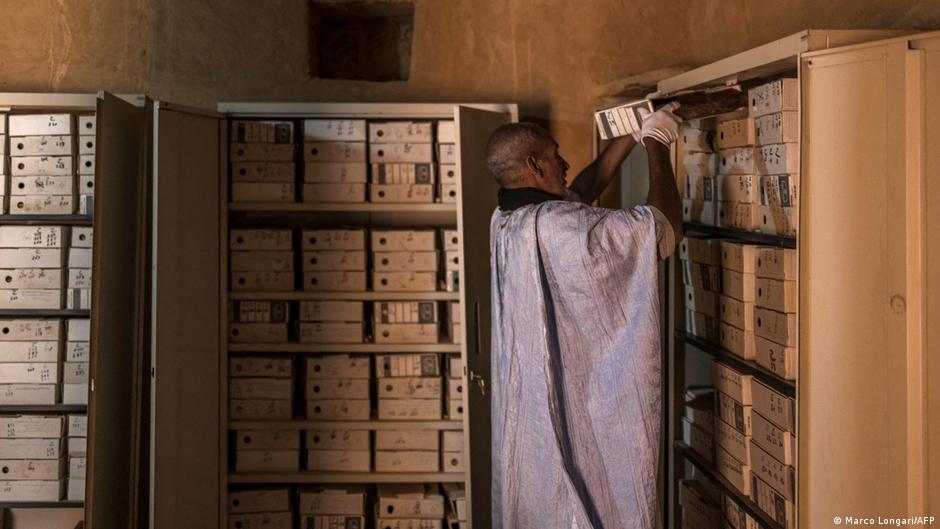 Abdullah Habbot retrieves a box of writings from a cabinet 