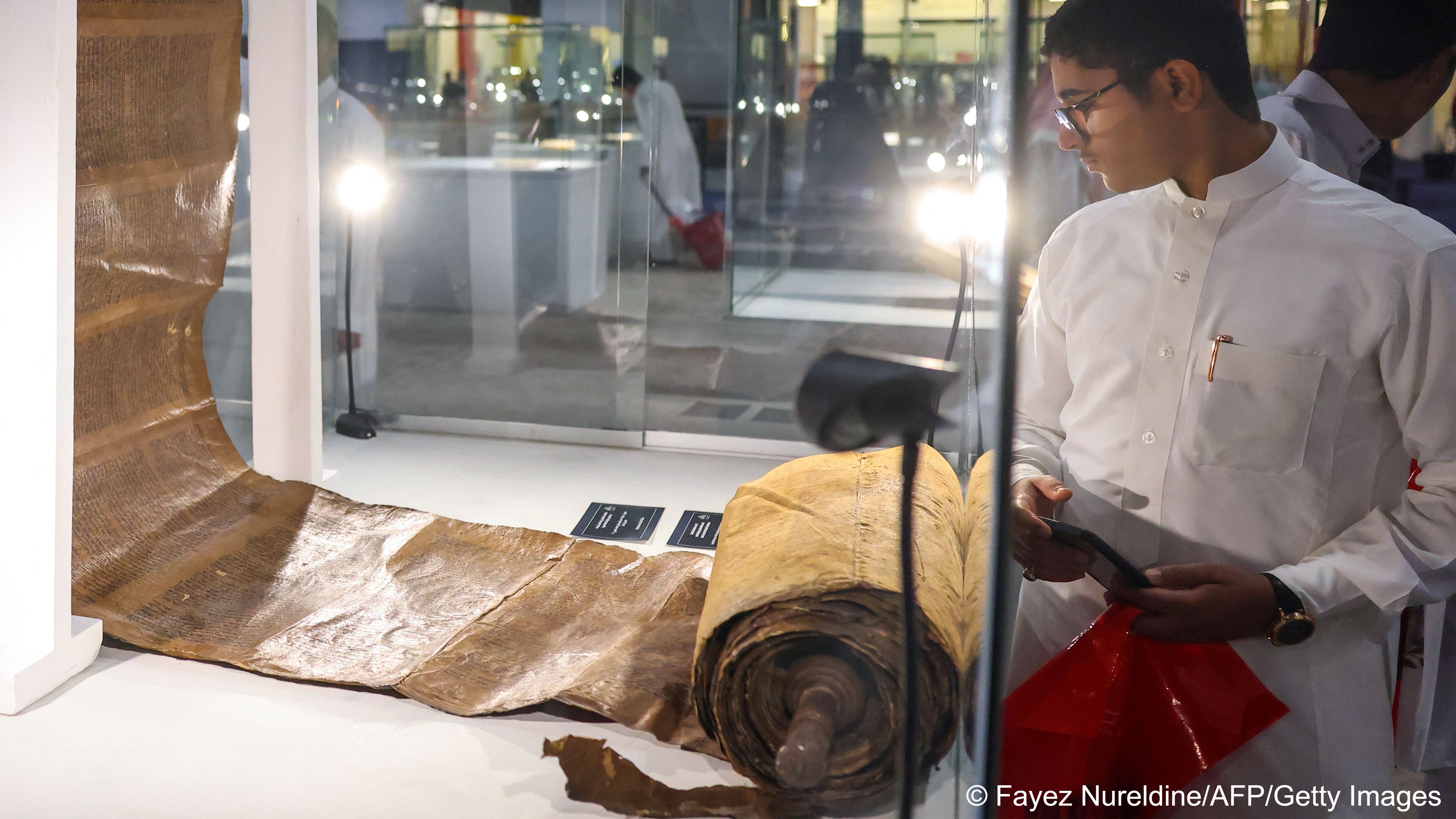 مخطوطة توراة من القرن الـ 16 في المعرض السعودي الدولي للكتاب بالرياض 2023. A man looks at a Torah scroll from the 16th century displayed at the Saudi International Book Fair in Riyadh on 4 October 2023 (image: Fayez Nureldine / AFP/File)