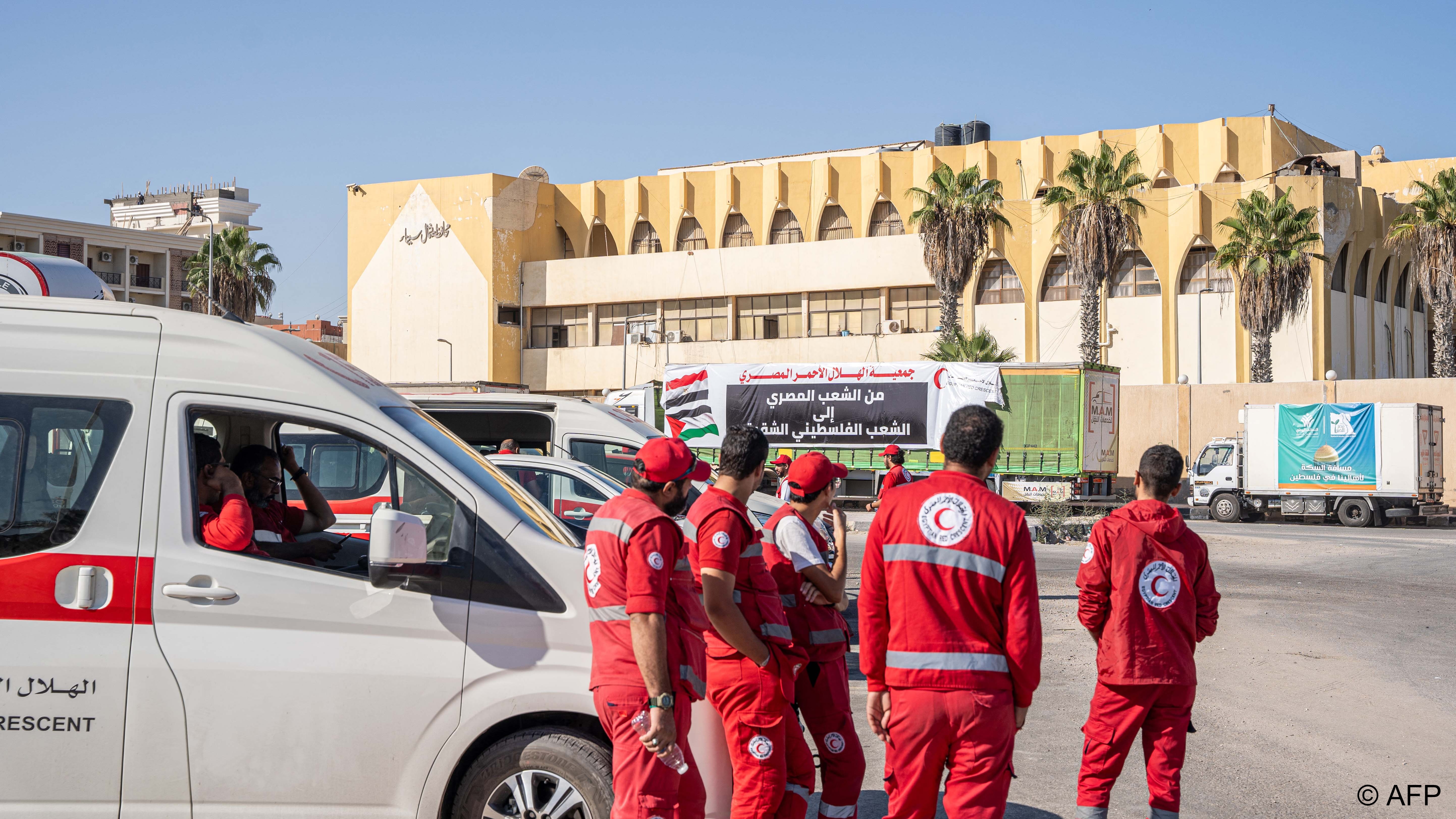 قافلة مساعدات مصرية عالقة على حدود قطاع غزة.Medics and a convoy of trucks loaded with aid supplies for Gaza provided by Egyptian NGOs wait for an agreement to cross through the Egypt-Gaza border (image: Ali Moustafa / AFP)