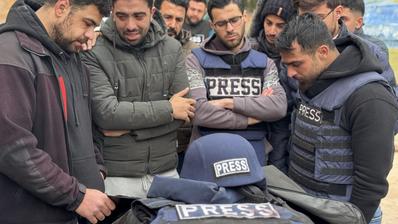 Men in press waistcoats stand around a laid-out body.