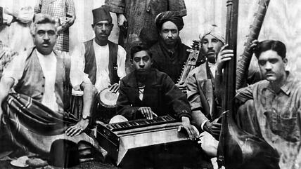 حيّ خرابات - منطقة الموسيقيين في كابول - أفغانستان source: www.kharabat.art A black and white image of a group of seated Afghan musicians posing with their instruments in Kharabat, Kabul