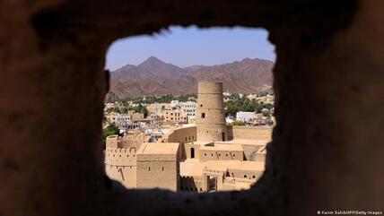 View of an old tower and city walls against the background of a blue sky and distant hills