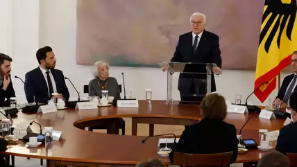 German President Frank-Walter Steinmeier stands next to a German flag and addresses representatives of Jewish and Muslim organisations