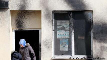 Two people stand outside a mosque after paint was sprayed on the façade of the building the night before, Leipzig, Germany, 20 April 2017