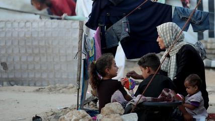 A mother sits with her children on the floor in a refugee camp in Gaza