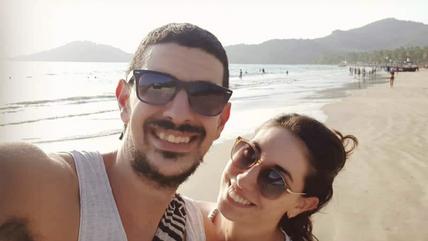 Selfie of a couple at the beach. They wear sunglasses.