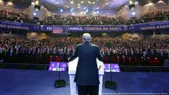 Turkish President Recep Tayyip Erdogan seen from behind standing at a podium on stage before a full auditorium