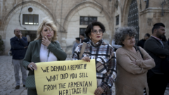 Drei Demonstrantinnen auf einem Platz in der Altstadt Jerusalems. Eine von ihnen hält ein Schild in den Händen, auf dem steht: Wir verlangen einen Bericht! Was vom armenischen Erbe habt ihr verkauft?"