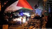 A man waves a Palestinian flag and others clash with anti riot policemen outside the Israeli consulate during a protest to show solidarity with Palestinians, Istanbul, Turkey, 18 October 2023