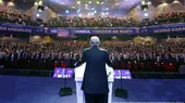 Turkish President Recep Tayyip Erdogan seen from behind standing at a podium on stage before a full auditorium