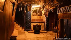 A woman kneels on a marble floor in front of a shrine said to mark the spot where Jesus was born