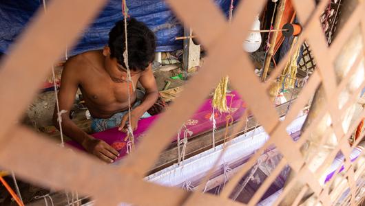 Ein kleiner Junge näht in Bangladesch einen Sari