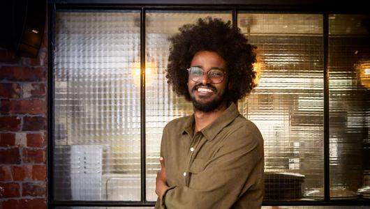 handsome black man smiles and holds his elbow